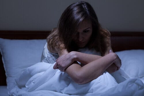 Eine Frau sitzt wach in ihrem Bett und kann nicht einschlafen