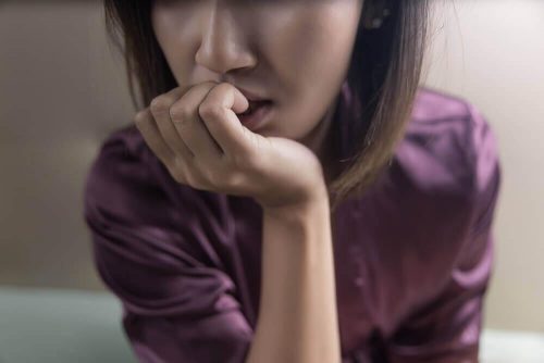 Frau mit obessivem Denken, die an ihren Nägeln kaut