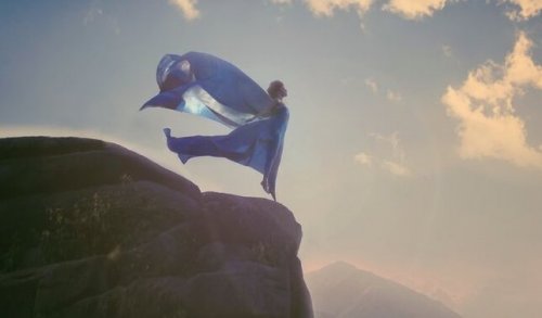 Frau in blauem Gewand an einer Klippe