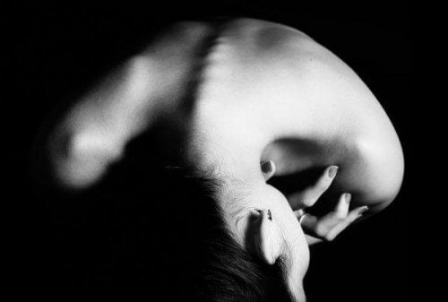 Ein Schwarz-Weiß-Bild einer nach vorne gebeugten Frau mit einer Essstörung.