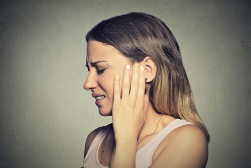 Frau, die an Tinnitus leidet, greift sich ans Ohr