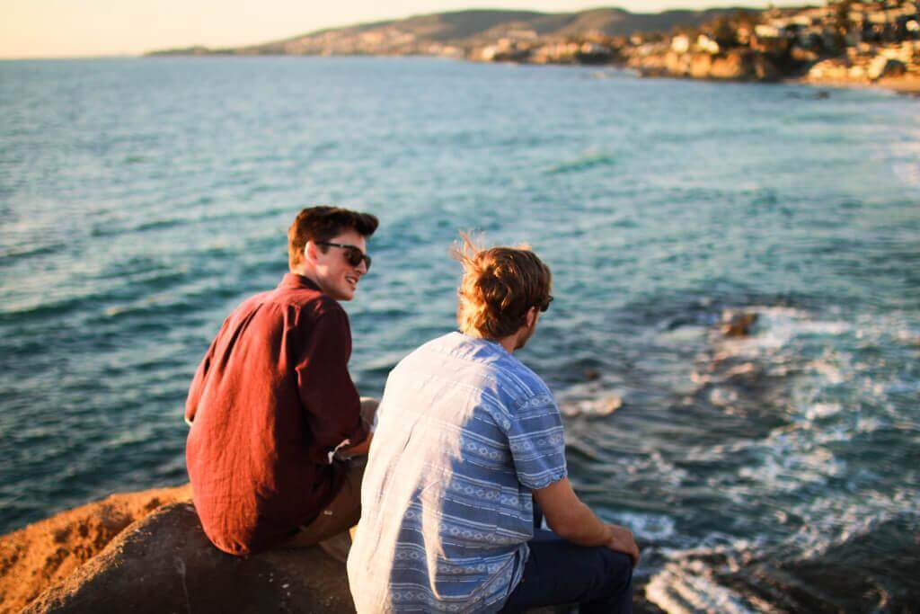 Zwei Freunde sitzen am Meer und unterhalten sich