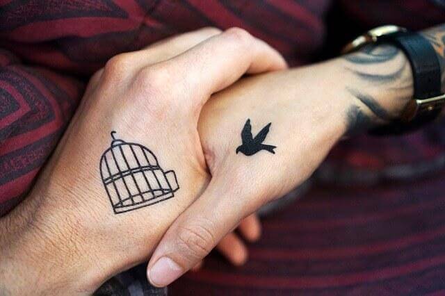 Alles für die Liebe aufgeben? - Paar hält sich an der Hand; einer der beiden trägt ein Tattoo eines Vogels und der andere eines Käfigs