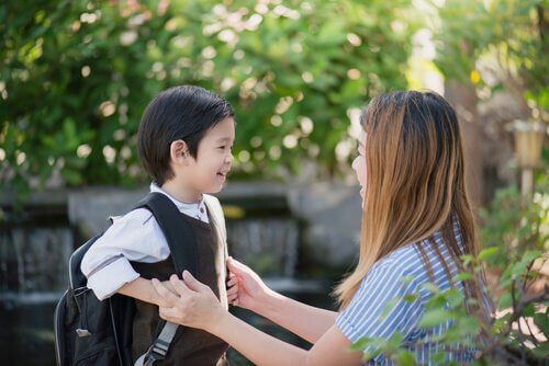 Junge mit Rucksack spricht mit seiner Mutter über die Schule