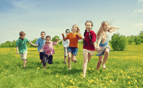 Eine Gruppe Kinder rennt über eine grüne Wiese.