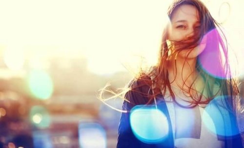 Lächelnde Frau mit Sonnenstrahlen im Hintergrund