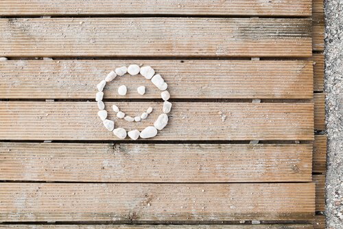 Lächelndes Gesicht aus Steinen auf Holzunterlage