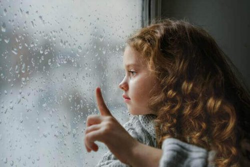 Mädchen schaut aus einem verregneten Fenster 