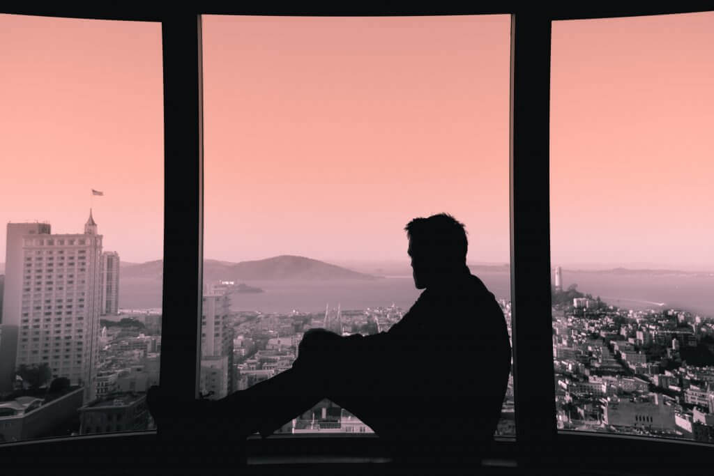 Mann sitzt allein an einem Fenster