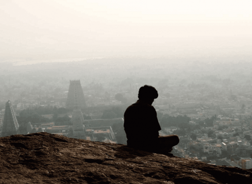 Mann betrachtet von einer Anhöhe aus die Stadt