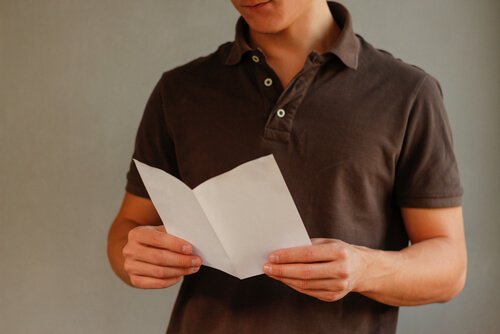 Ein junger Mann hält einen gefalteten Zettel in seinen Händen.