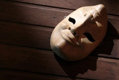 Eine Maske, die ein lächelndes und trauriges Gesicht zeigt, liegt auf dem Boden. 