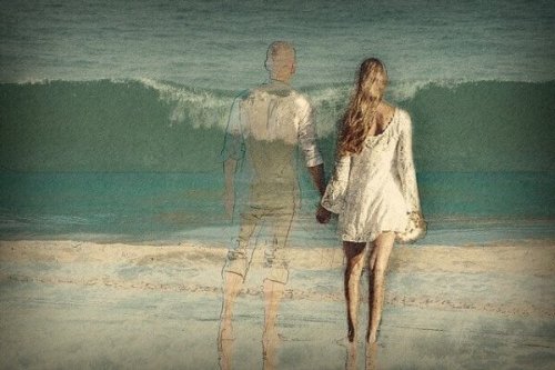 Ein Paar geht Hand in Hand am Strand spazieren; der Mann ist nur transparent zu sehen.