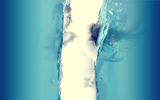 Paar steht sich unter Wasser gegenüber