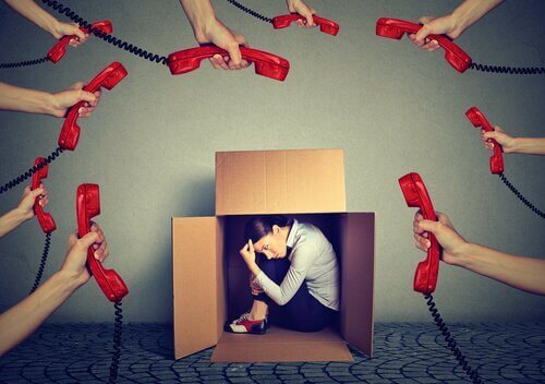 Eine Frau versteckt sich in einem Karton, während viele Telefone klingeln.
