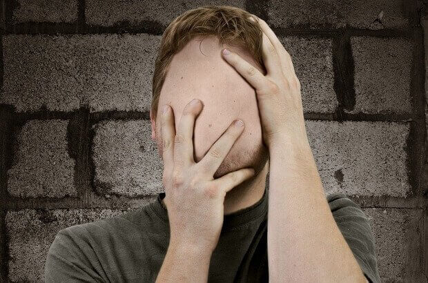 Mann ohne Gesicht fasst sich an den Kopf