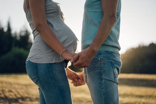 Schwangere Frau und ihr Partner halten Händchen