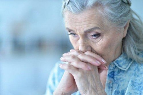 Seniorin kämpft gegen Niedergeschlagenheit, hält sich die Hände vor das Gesicht.