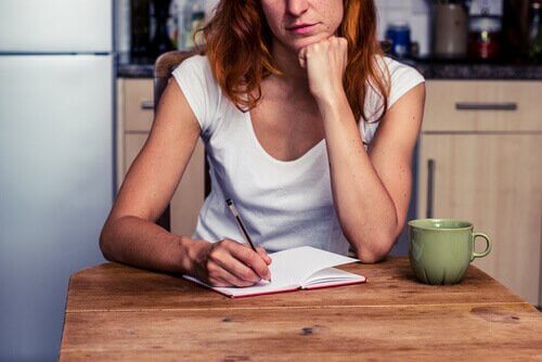 Frau schreibt Tagebuch am Tisch