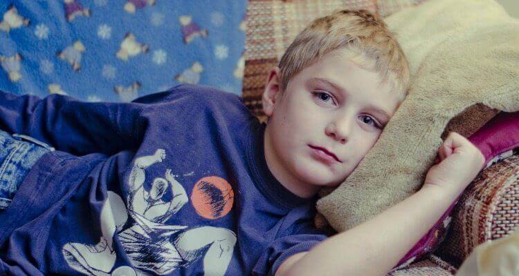 Junge liegt krank auf dem Sofa