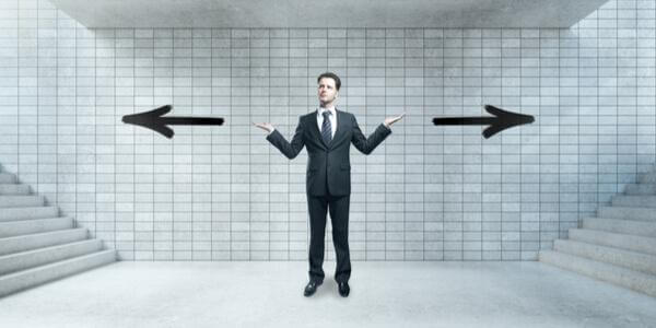 Mann steht vor zwei Treppen und weiß nicht, welche er nehmen soll