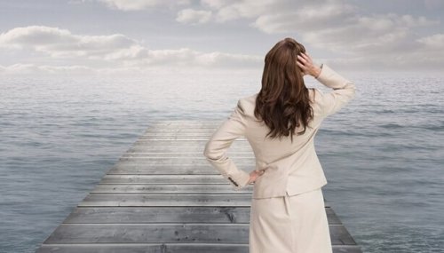 Eine Frau steht auf einer Brücke und schaut auf das Meer.