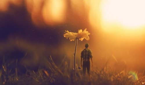 Winziger Mann steht neben einer Blume