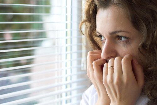 Eine Frau sieht ängstlich aus dem Fenster.