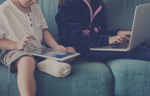Zwei Kinder mit Tablet und Notebook