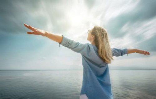 Frau mit ausgestreckten Armen am Meer