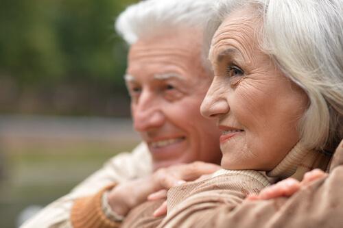 Älteres, zufriedenes Ehepaar schaut lachend in die Ferne