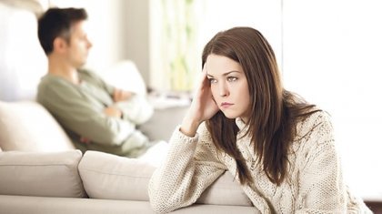 Eine frustrierte Frau und ihr Partner in einem Zimmer