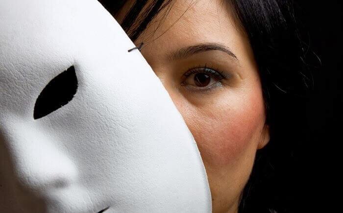 Frau schaut hinter einer weißen Maske hervor