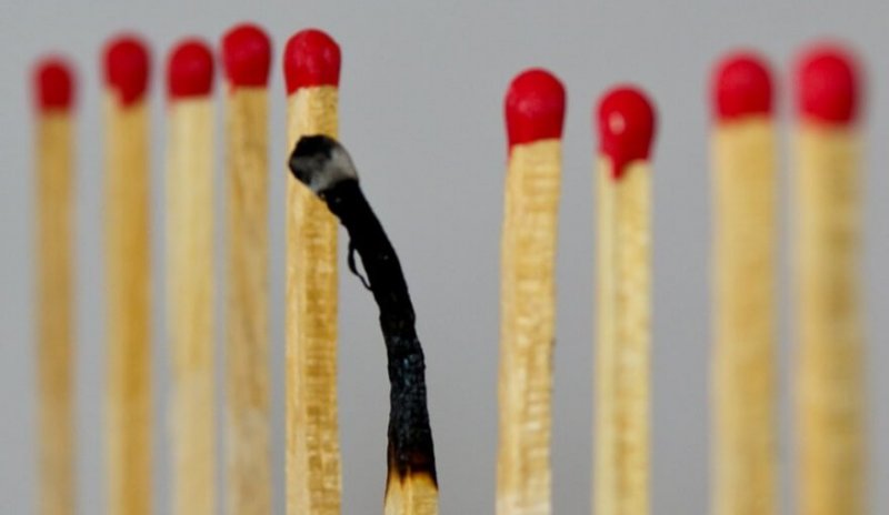 Ein abgebranntes Streichholz inmitten neuer Streichhölzer