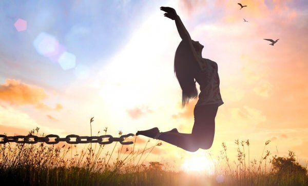 Eine Frau springt und befreit sich aus ihren Ketten.