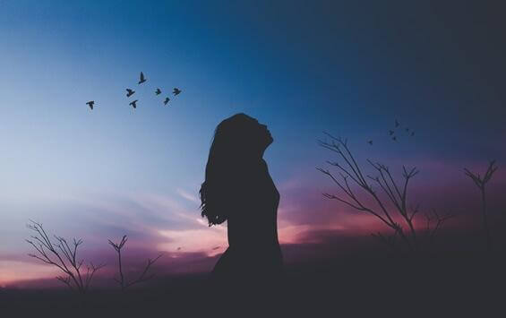 Frau umgeben von Vögeln im Morgengrauen