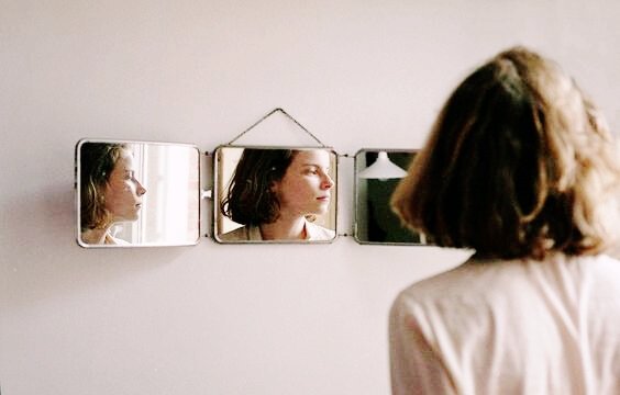 Frau betrachtet sich im Spiegel