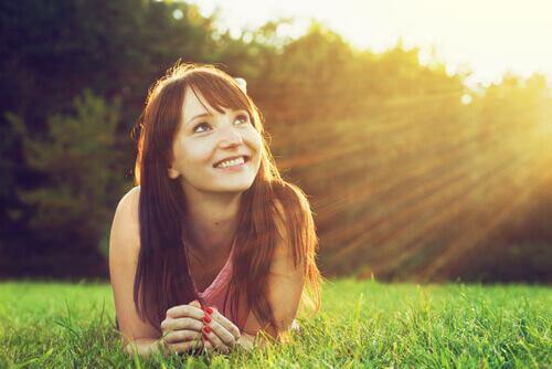 Eine Frau liegt lächelnd im Gras. 