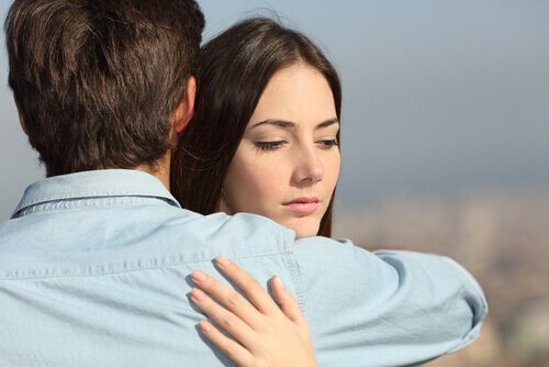 Ein Mann und eine Frau umarmen sich, während die Frau misstrauisch schaut.