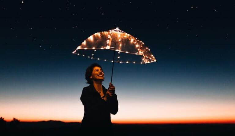 Lachende Frau hält einen leuchtenden Schirm