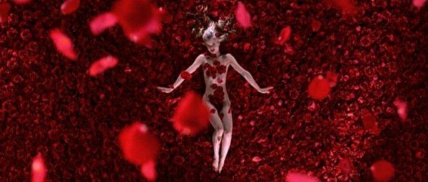 Filmszene aus American Beauty, auf der sich ein nacktes Mädchen auf Rosenblättern rekelt. 