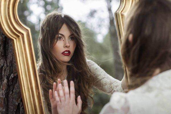Frau mit Selbstzweifeln schaut in den Spiegel.