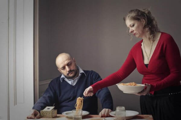 Eine Frau tischt das Essen für einen Mann auf. 
