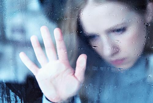 Frau blickt traurig aus einem Fenster