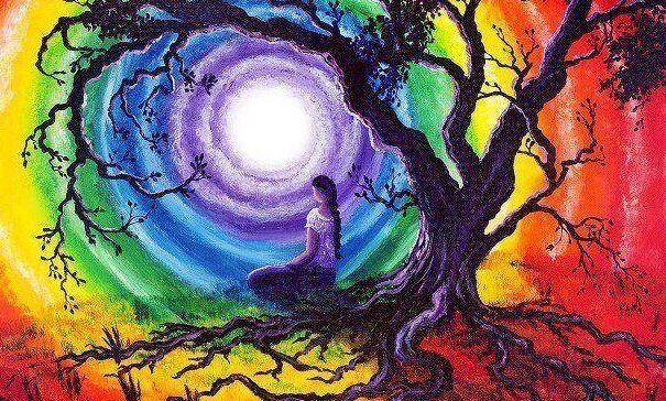 Frau, die auf einem Baum sitzt und in einen Himmel in Regenbogenfarben schaut