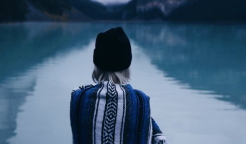 Frau steht vor einem See