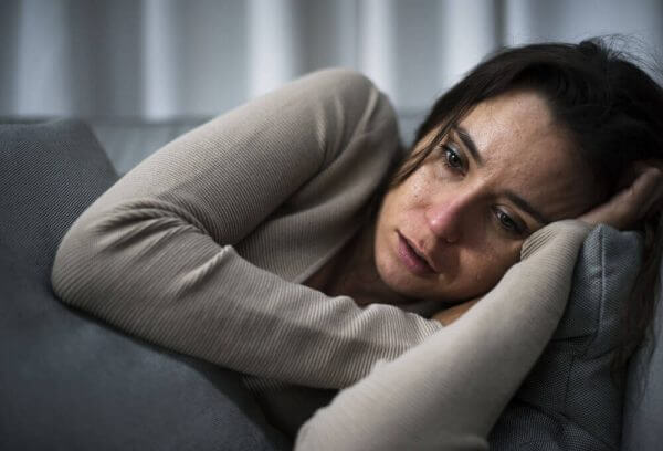 Eine Frau weint auf der Couch.