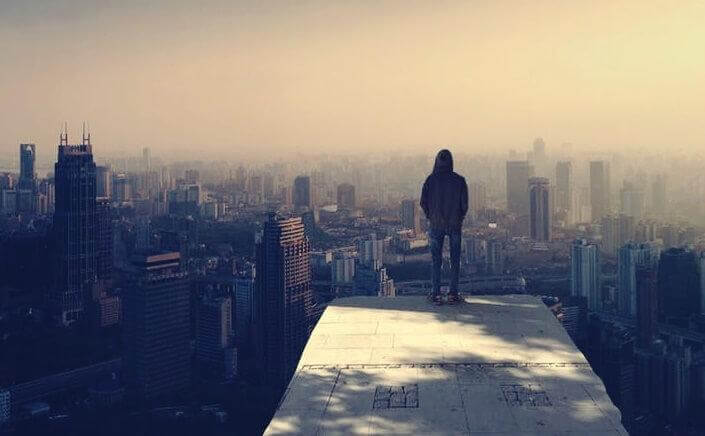 Mann steht auf einem Gebäude und schaut auf eine Stadt hinunter