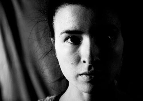 Das ernste Gesicht einer Frau, das halbseitig von einem Schatten verdeckt wird