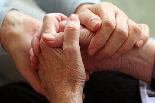 Ein junger Mensch und ein älterer Mensch halten sich an den Händen. 